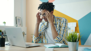Person sits at computer with fingers on their temples